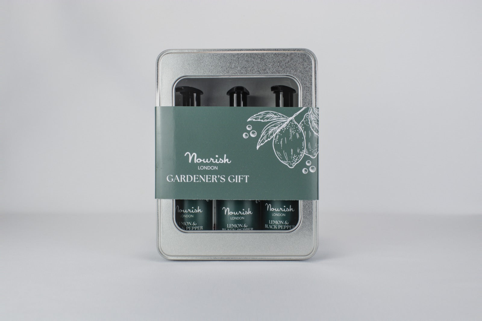 Silver tin gardener's gift set with green band containing three black pump bottles with lemon and black pepper labeling