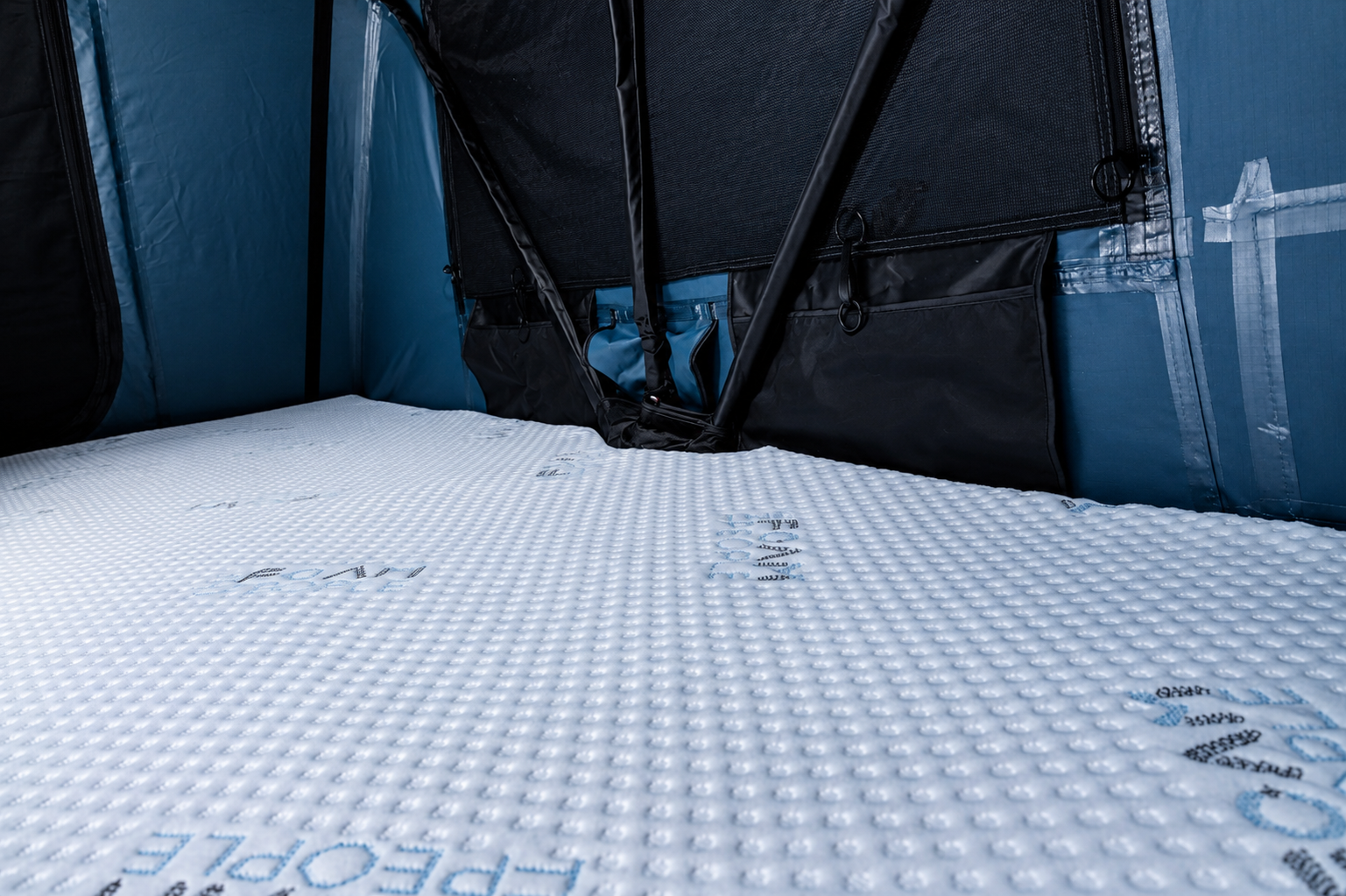White quilted foam mattress with textured surface inside dark-colored storage bag with black straps