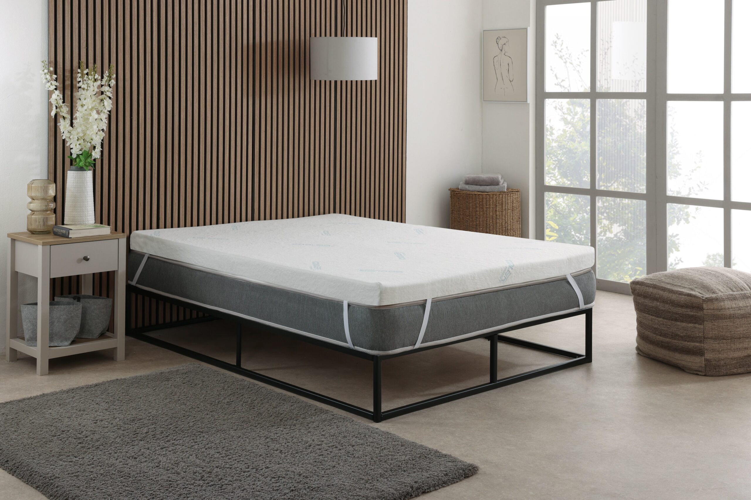 White foam mattress displayed on black metal bed frame in modern bedroom with wood slat accent wall